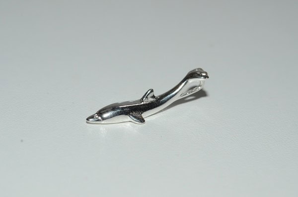 Un pendentif argenté en forme de dauphin évoque l'élégance et la liberté des profondeurs marines, parfait pour les passion...
