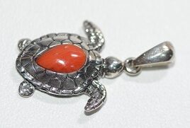 Un pendentif en forme de tortue avec une pierre rouge évoque l'élégance marine, parfait pour les passionnés de plongée.