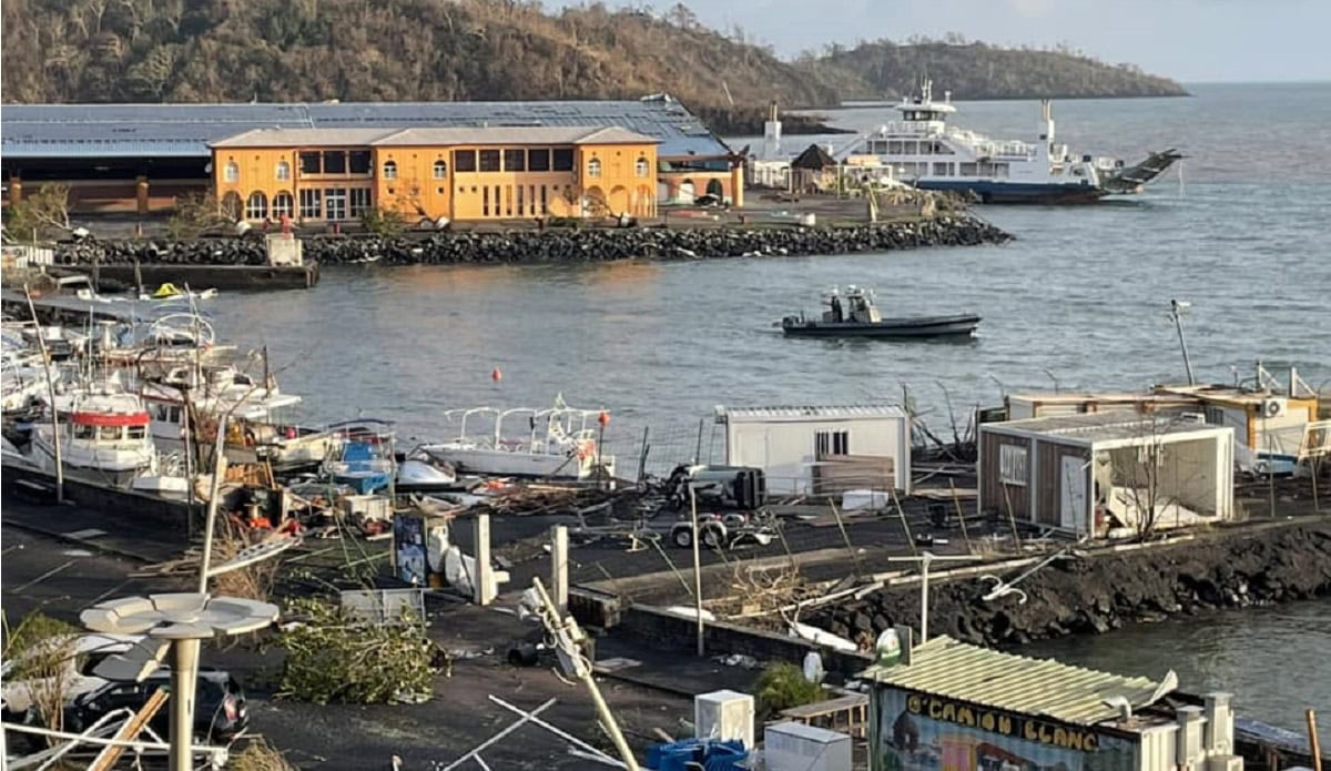 Un port tropical montre des bateaux endommagés après une tempête, soulignant l'importance de la résilience maritime.