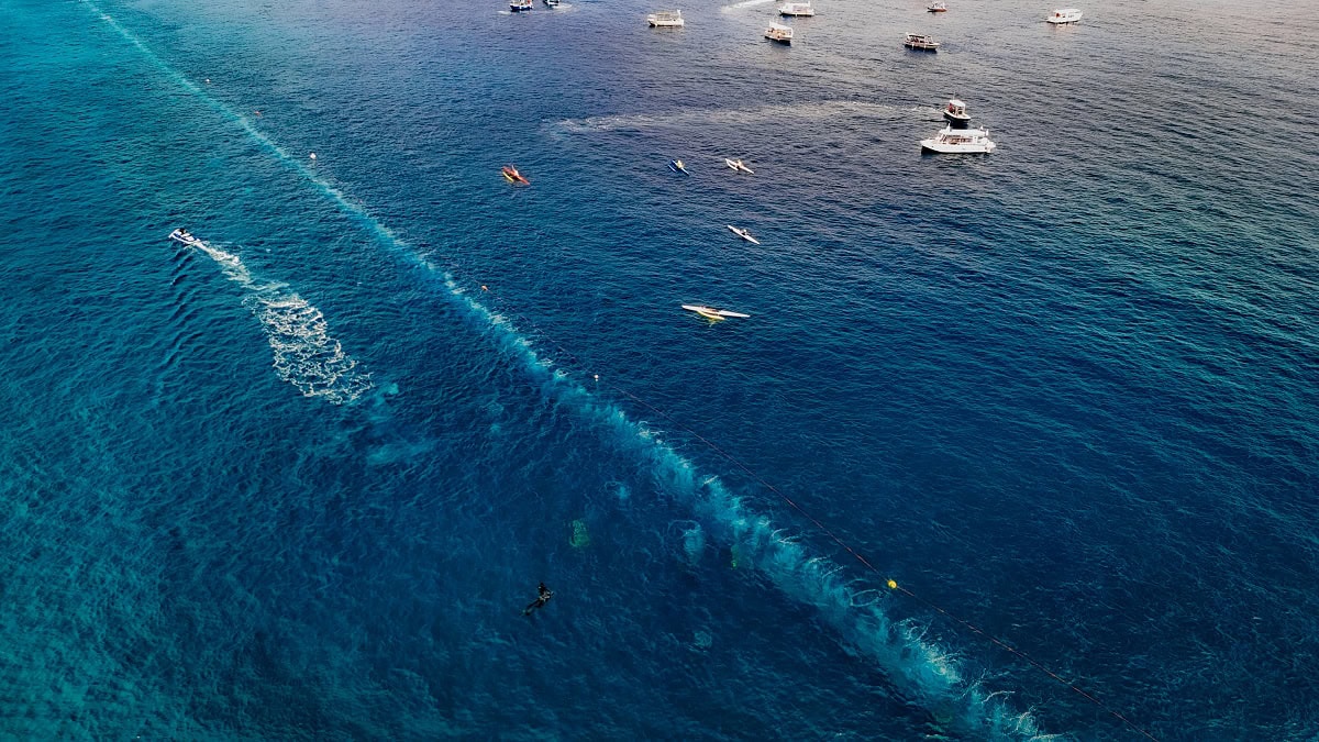 Des bateaux flottent paisiblement au-dessus d'une barrière de corail, offrant un spectacle marin captivant pour les amateu...