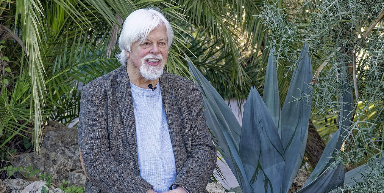 Un homme souriant est assis parmi des plantes luxuriantes, évoquant une connexion sereine avec la nature marine. #Écologie