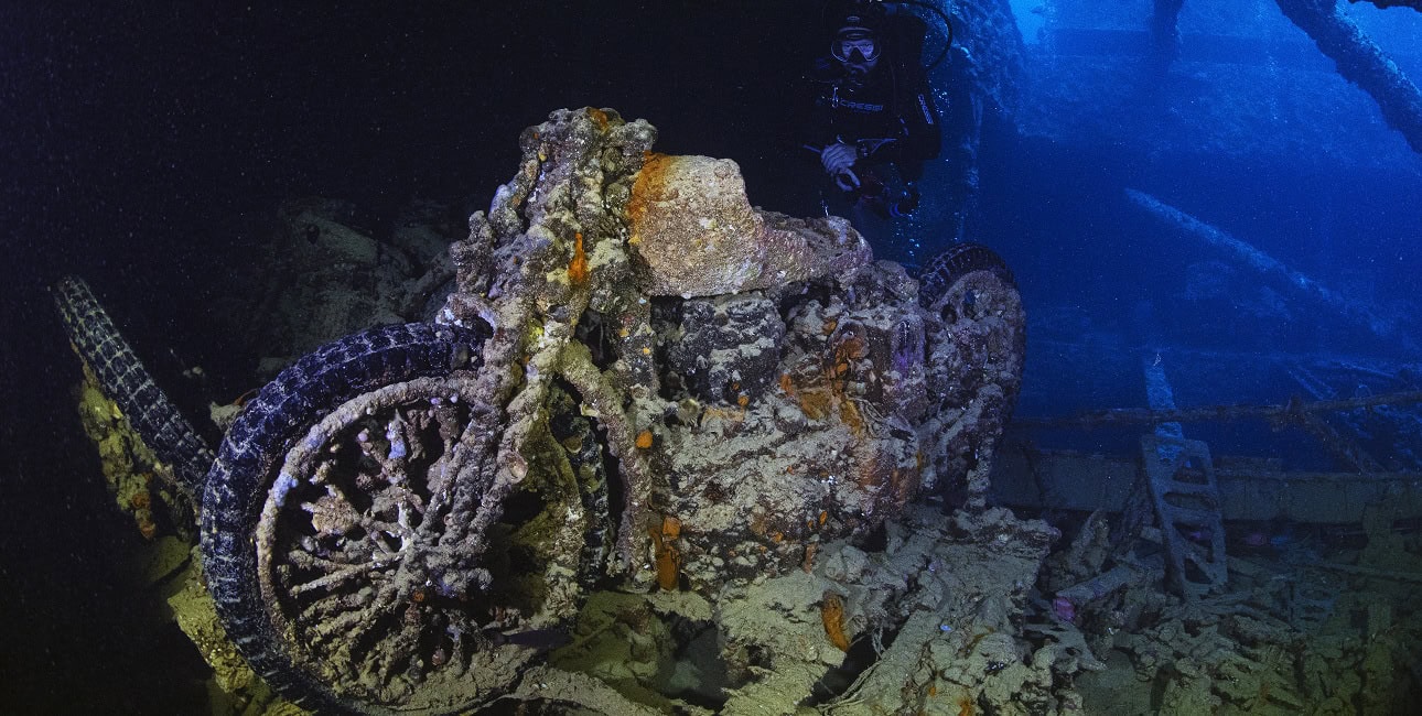 Un plongeur explore une épave recouverte de coraux, révélant une moto engloutie dans les profondeurs mystérieuses de la me...