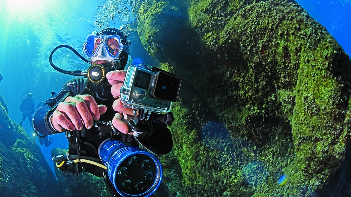 Un plongeur explore les profondeurs marines, caméra à la main, capturant la beauté sous-marine pour des souvenirs d'aventu...