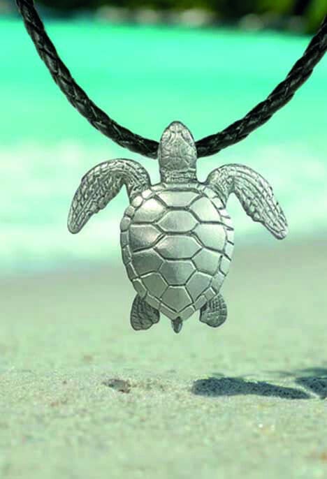 Un pendentif tortue évoque l'évasion marine sur une plage ensoleillée, symbole de la beauté de l'océan.