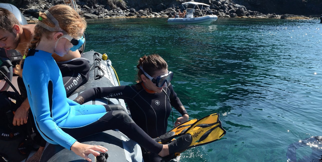 Deux plongeuses en combinaison se préparent à explorer les eaux cristallines depuis un bateau, prêtes pour l'aventure sous...