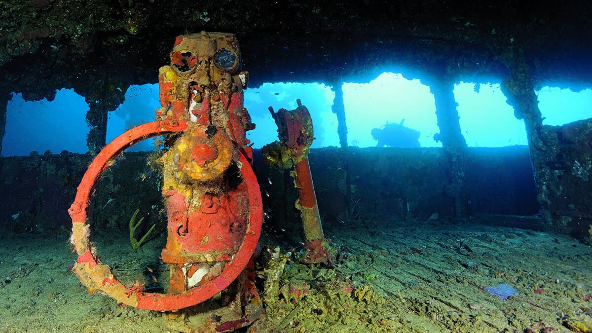 Un plongeur explore l'intérieur mystérieux et rouillé d'une épave sous-marine, témoin silencieux de l'histoire maritime. #...