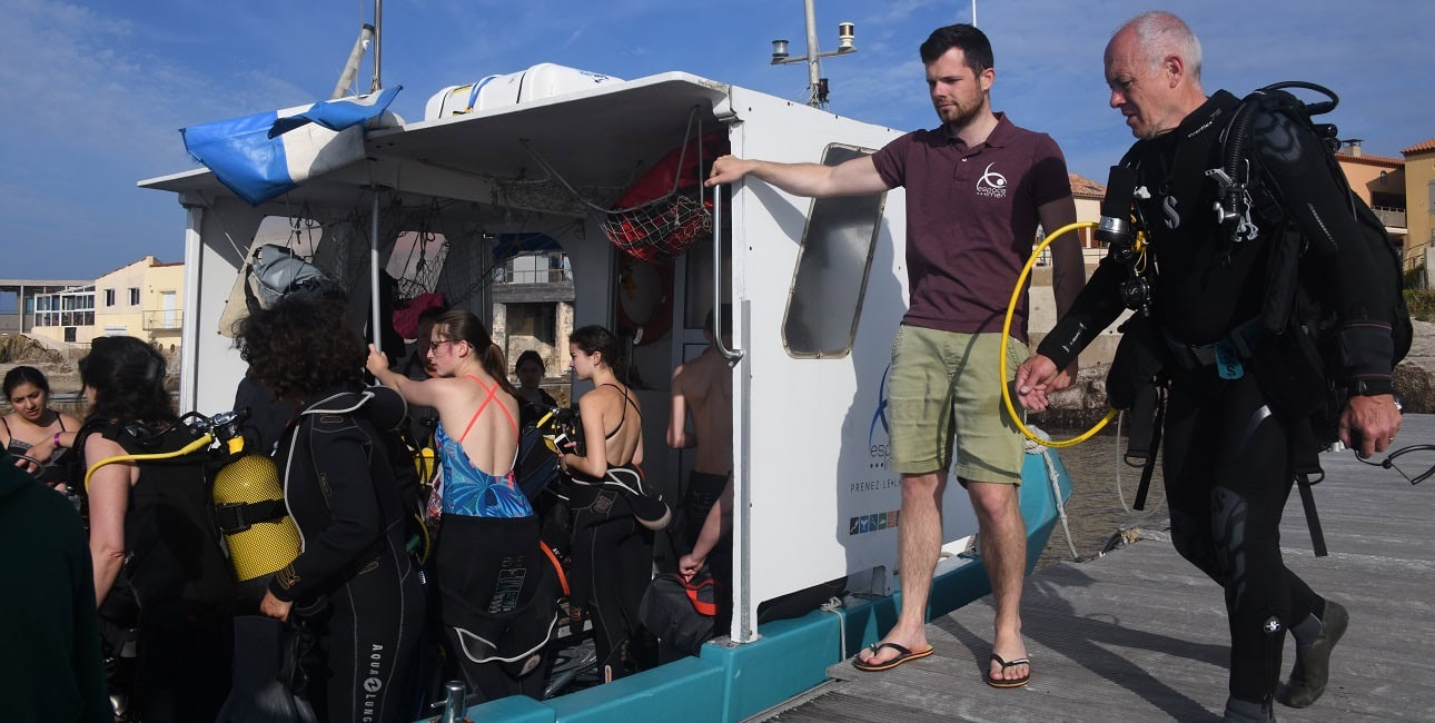 Des plongeurs se préparent à embarquer pour une aventure sous-marine, mettant en avant l'exploration marine.