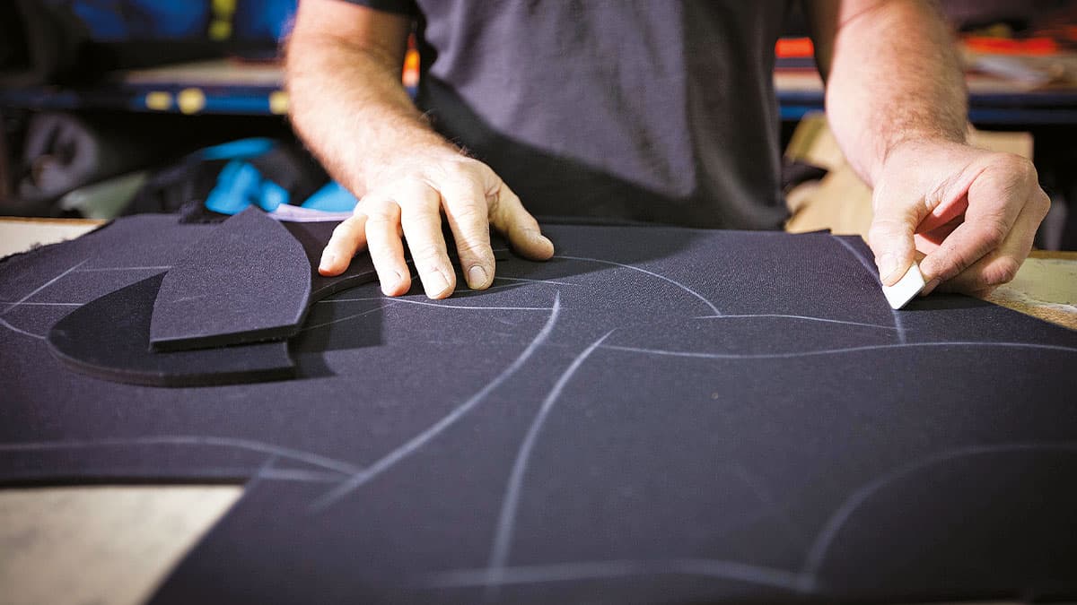 Un artisan trace des motifs sur du néoprène pour créer une combinaison de plongée sur mesure, essentielle pour l'explorati...