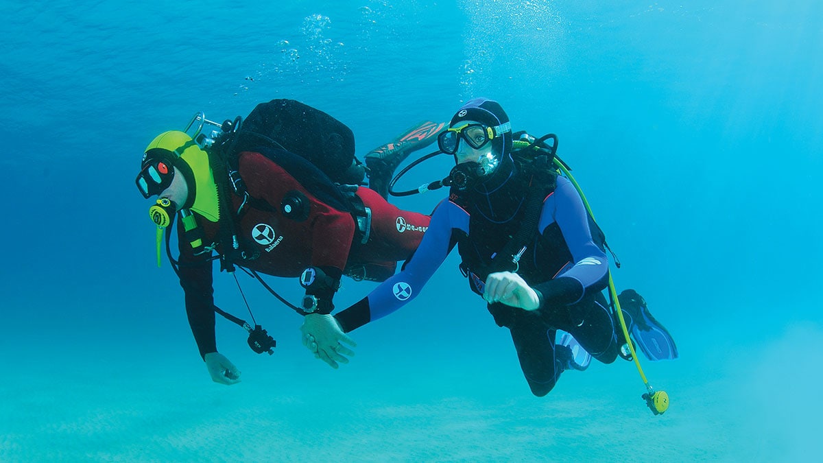 Deux plongeurs explorent les profondeurs cristallines, illustrant l'aventure sous-marine et la beauté de l'océan.
