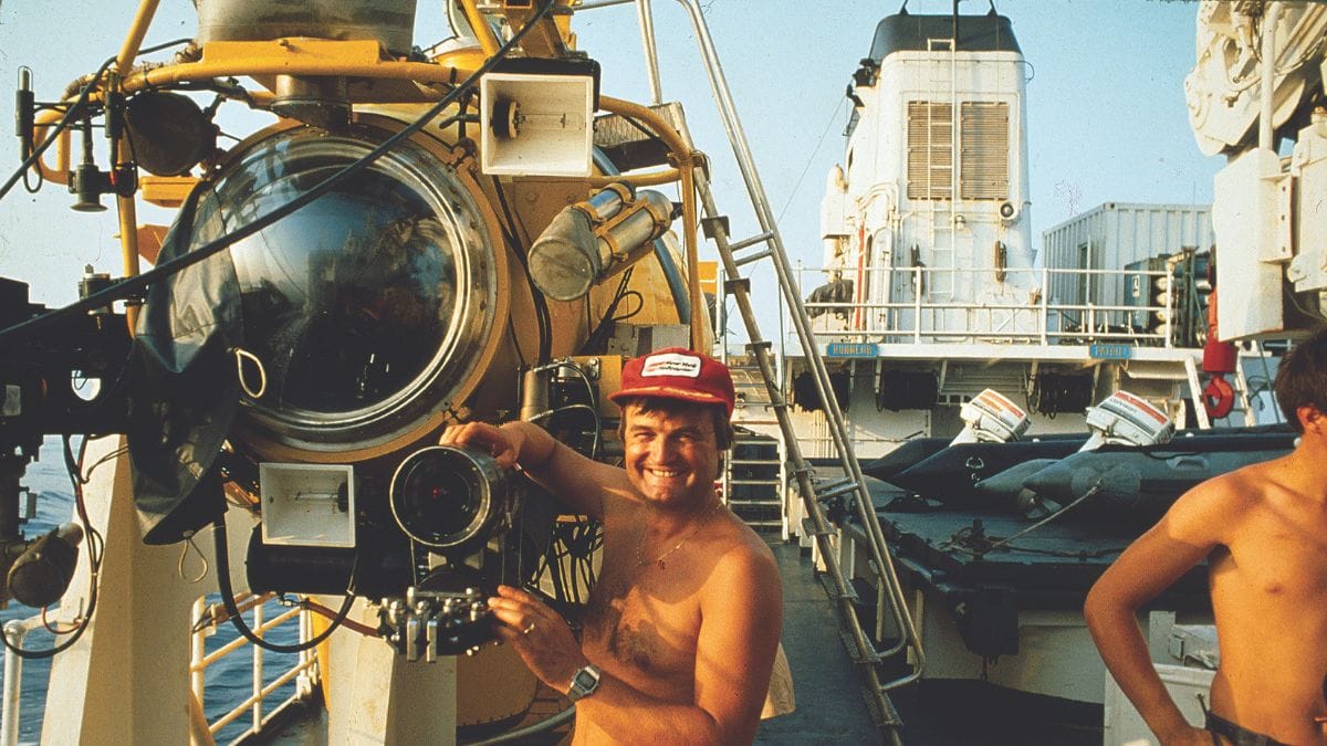 Un plongeur souriant prépare un submersible pour une exploration marine, symbole d'aventure sous-marine.