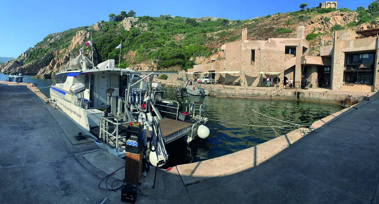 Un bateau de recherche amarré à STARESO, en Corse, prêt pour une exploration scientifique des richesses marines.