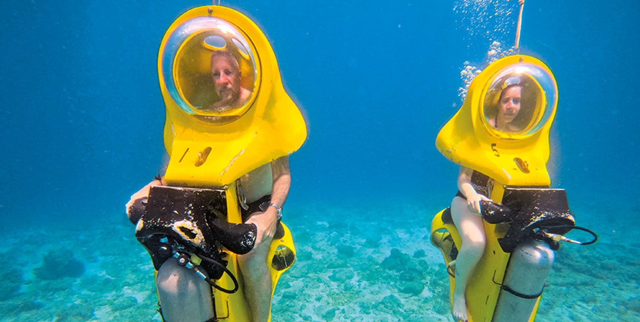 Deux plongeurs explorent les fonds marins sur des scooters sous-marins, offrant une aventure unique et écologique.