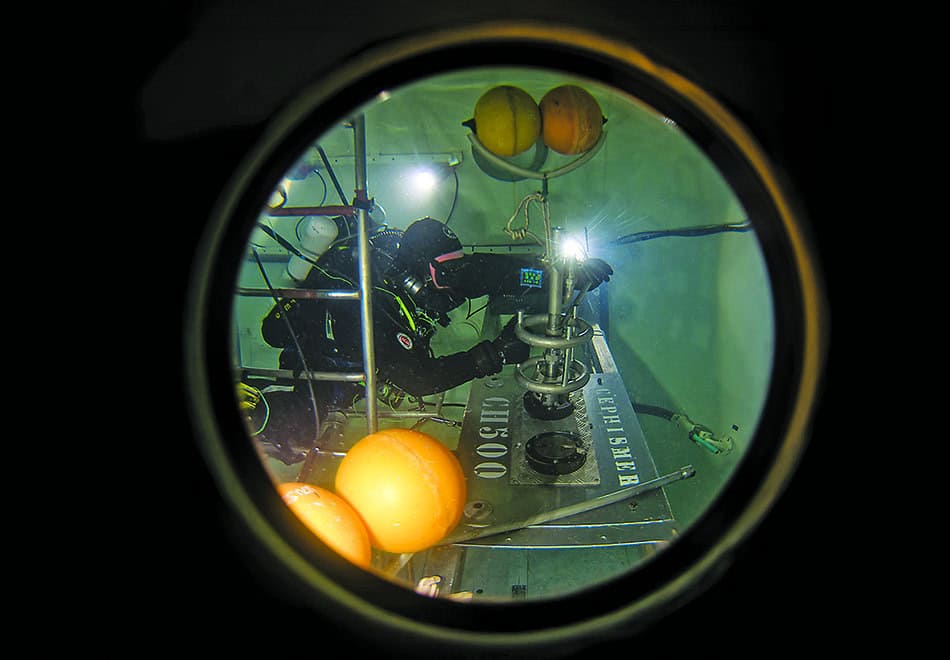 Un plongeur effectue des recherches sous-marines avec des équipements spécialisés dans un environnement aquatique.