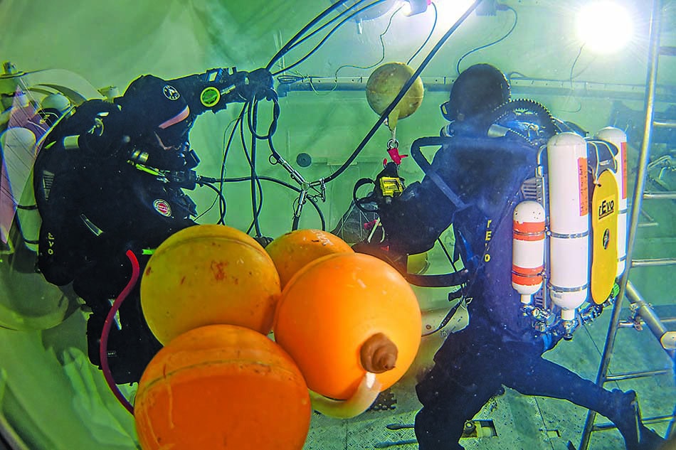 Des plongeurs équipés travaillent sous l'eau, utilisant des bouées pour des missions sous-marines.