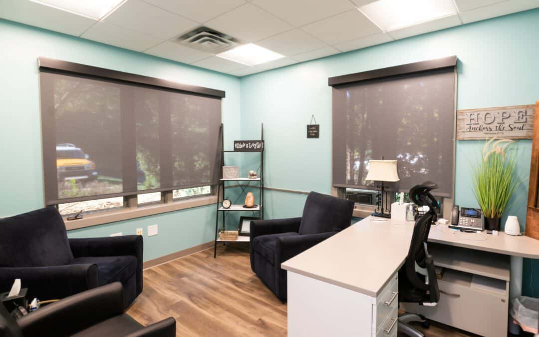 Comfortable medical consultation room with chairs, desk, and window blinds.