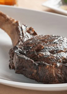 Juicy grilled steak with seasoning on a white plate at Prime Steakhouse.