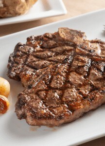 Juicy, perfectly grilled steak with seared grill marks on a white plate.