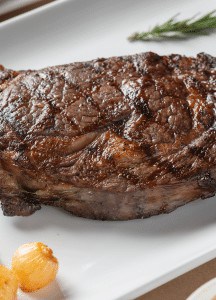 Juicy, well-cooked steak with crispy exterior on a white plate at Prime Steakhouse.