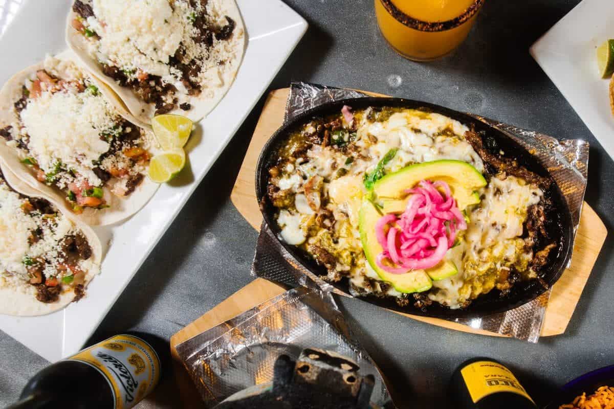 Loaded fajita skillet with grilled meat, avocado, and vibrant tacos—signature dishes from Pure Mex Byron Center’s menu.