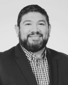 Headshot of Ramon R. in a suit and checkered shirt.