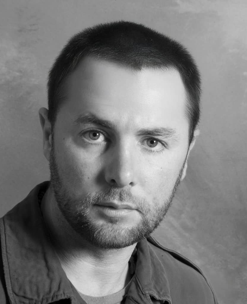 Black and white portrait of a man with short hair and beard.