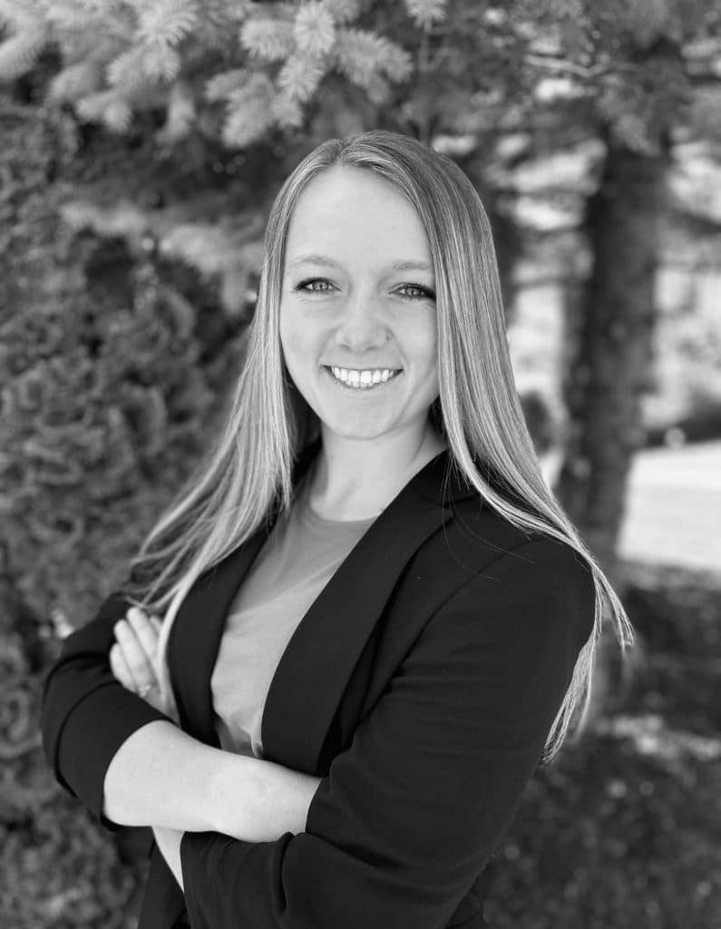 Portrait of Jennifer R. smiling outdoors with trees in background.