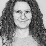 Portrait of Jo Smiley H. with curly hair and glasses in black and white.