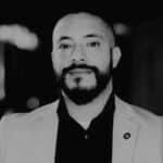 Black and white portrait of Alvaro P. with beard and suit.