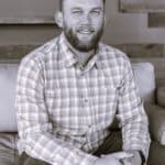 Portrait of Brandon F. smiling, sitting on a sofa in a casual setting.