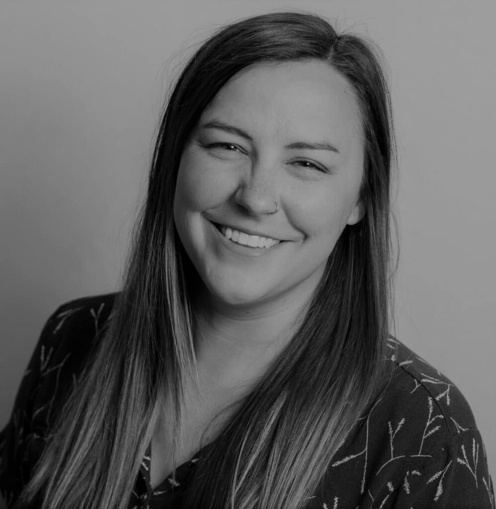 Portrait of Brittany A. smiling, professional headshot in black and white.