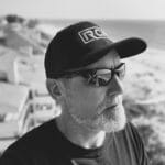 Man wearing RC cap and sunglasses at the beach in black and white.