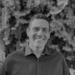 Portrait of a smiling man in front of trees, black and white photo.