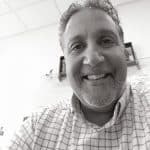 Black and white photo of Dan A. smiling in an office setting.