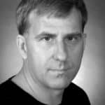 Black and white portrait of a man with short hair and serious expression.