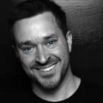 Black and white photo of a man with blue eyes and a friendly smile.