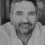Black and white portrait of a smiling man with short hair and beard.
