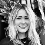Black and white portrait of a smiling woman with long hair.