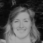 Smiling woman with sunglasses on her head outdoors in black and white.