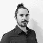 Black and white portrait of a man with a bun hairstyle and a beard.