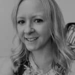 Portrait of a woman with blonde hair smiling, in grayscale.