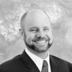 Smiling man in suit with a beard, professional headshot.