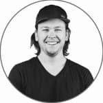 Smiling man with long hair and cap, black and white photo.