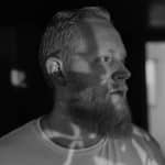 Black and white profile photo of a bearded man with short hair.