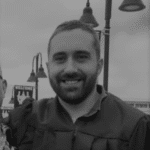 John Green, project manager, smiling outdoors with street lamps in background.