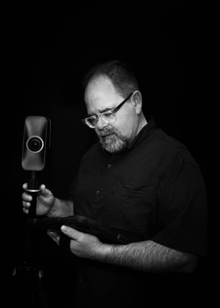 Man with glasses operating 3D laser scanner for reality capture.