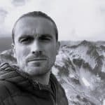 Black and white photo of a man with mountains in the background.