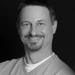 Portrait of Larry G. smiling, professional headshot in black and white.