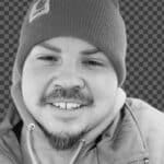 Portrait of Levi C. wearing a beanie and jacket, smiling at the camera.