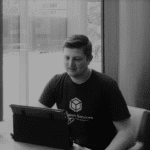 Young man working on tablet in office setting with window view.