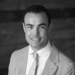 Headshot of Matthew T. in a suit, smiling, professional setting.